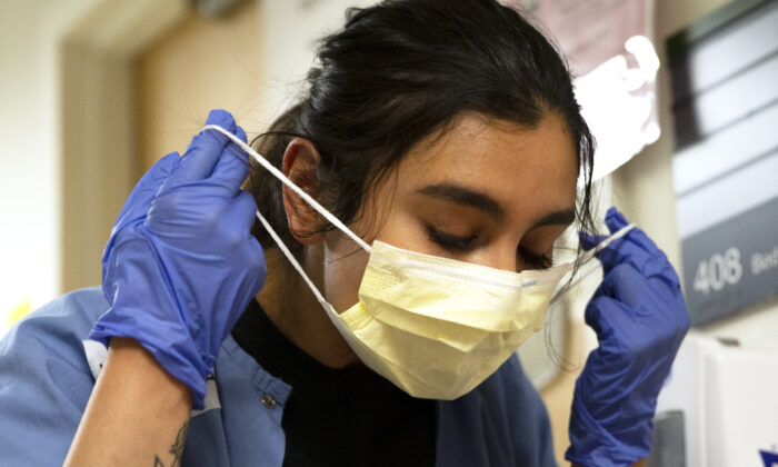 A nurse carefully removes her mask and PPE after tending to a patient with COVID-19 in the acute care COVID unit at Harborview Medical Center on May 7, 2020 in Seattle, Washington. (Karen Ducey/Getty Images)