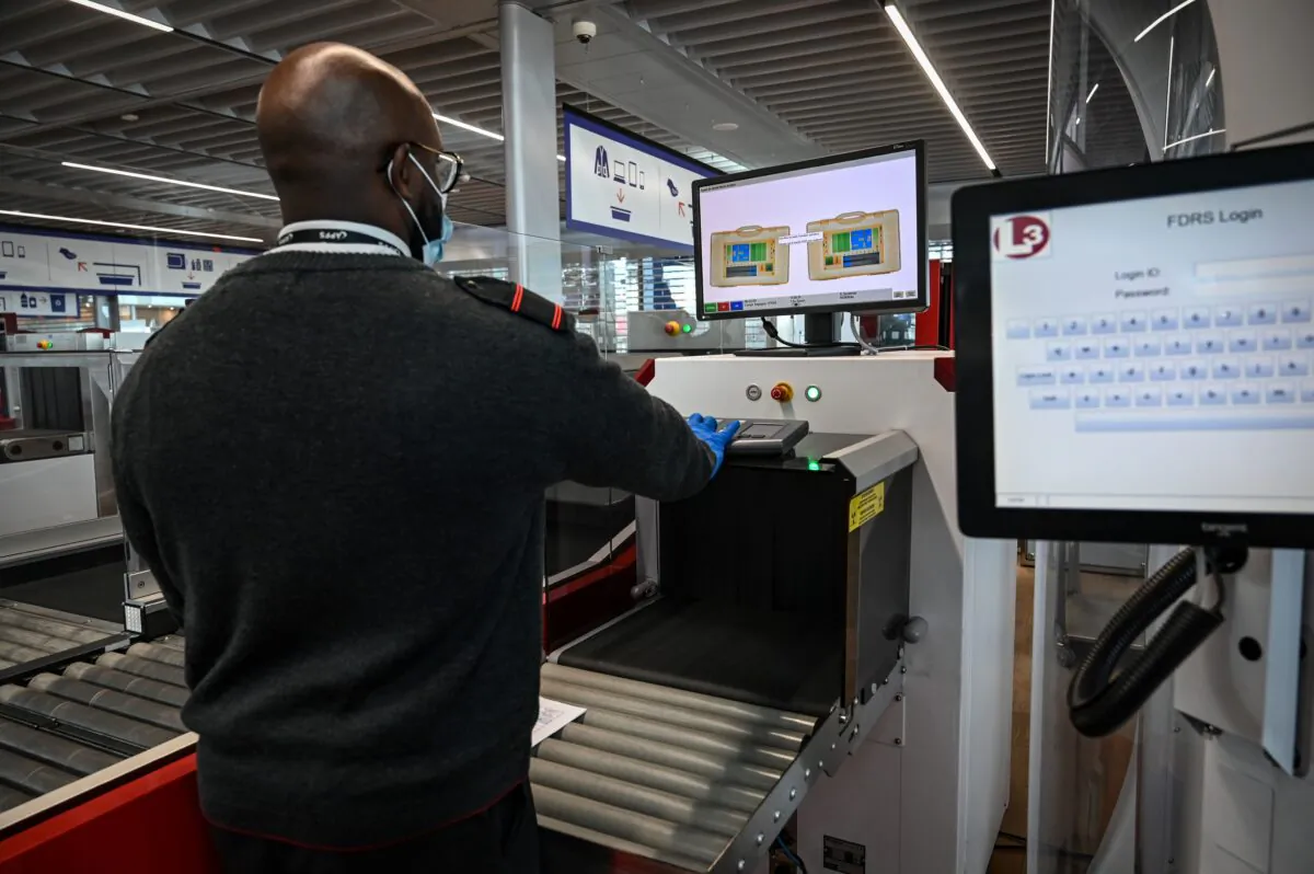 An airport staff member checks passengers' luggage passing through an X-ray machine at the Terminal 3 of the Orly airport, in Orly, on the outskirts of Paris, on June 22, 2020. (BERTRAND GUAY/AFP via Getty Images)