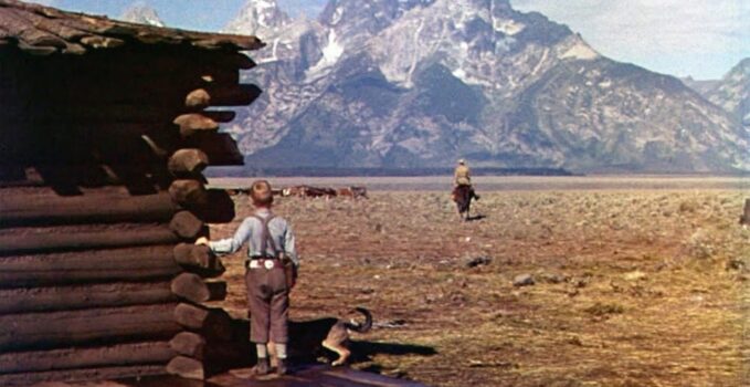 boy watching a man ride toward mountains