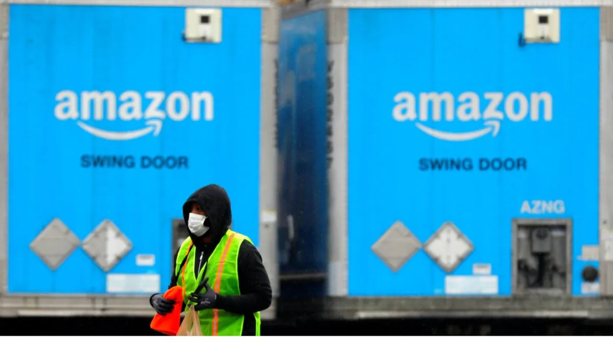 A worker in a face mask walks by trucks parked at an Amazon facility as the global coronavirus (COVID-19) outbreak continued in Bethpage on Long Island in New York, on March 17, 2020. (Andrew Kelly/Reuters)