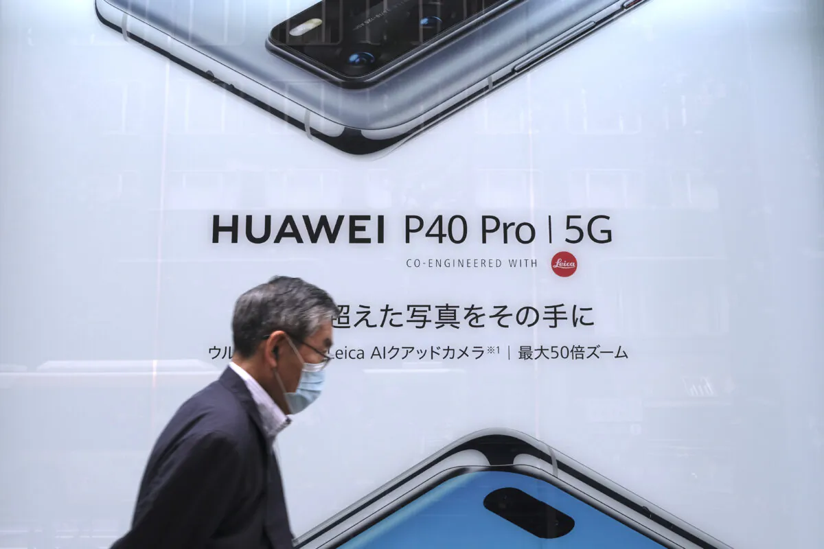In this picture taken on June 27, 2020, a man walks past an advertisement for the latest smartphone by Chinese telecommunications company Huawei in Tokyo. (KAZUHIRO NOGI/AFP via Getty Images)
