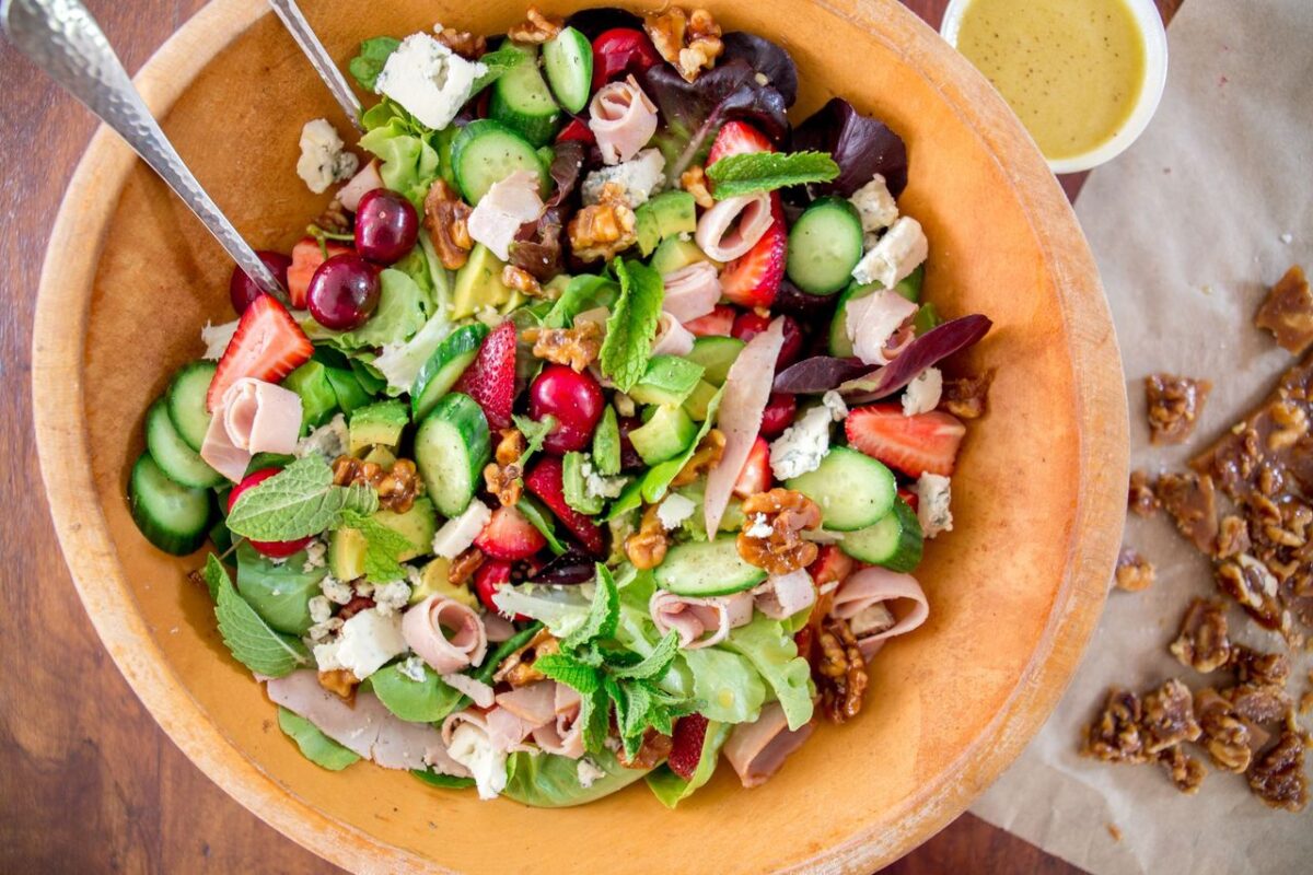 This salad features an ensemble cast—sweet berries, ham, cheese, cucumbers, avocado, and greens—in a star dressing.