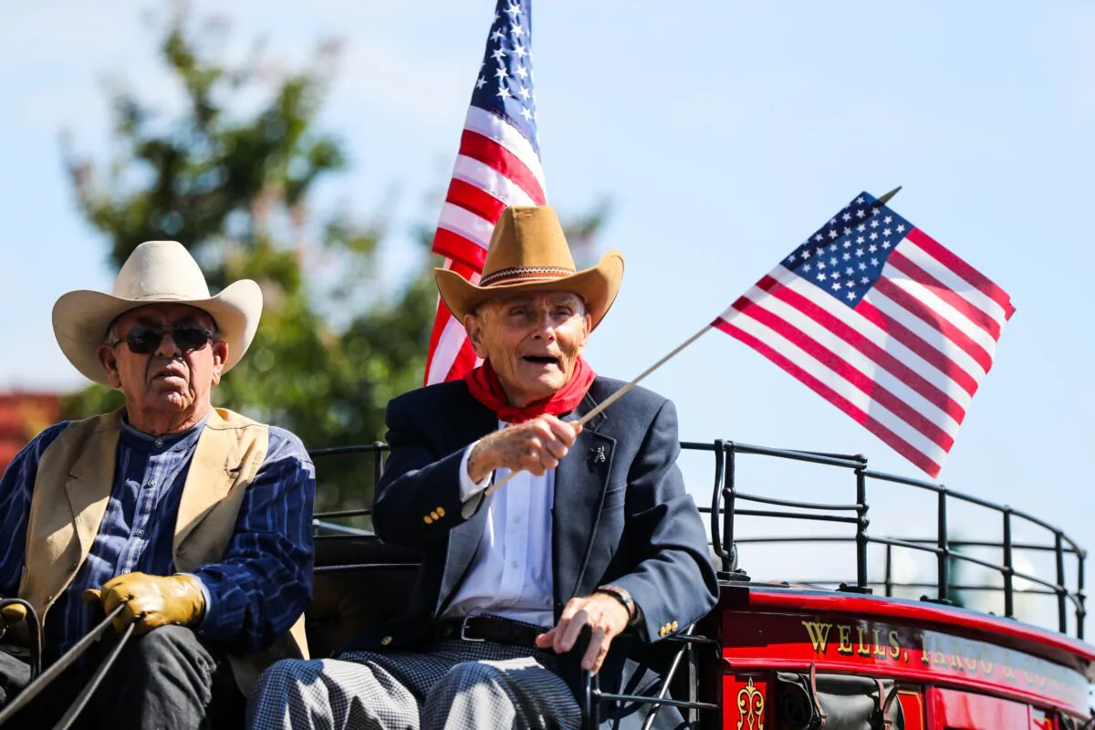 A man waves an American flag while riding a carriage at the Fourth of July parade, in Alameda, Calif., on July 4, 2016. (Gabrielle Lurie/AFP via Getty Images)