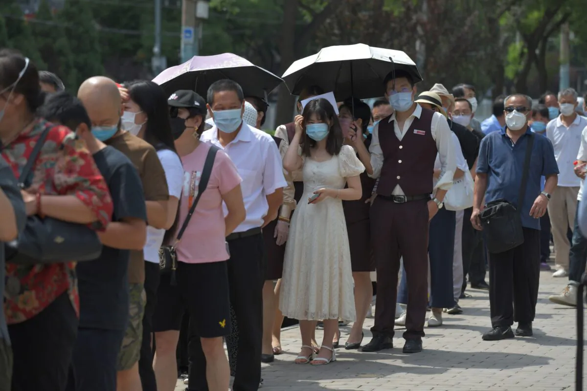 People wait in line to undergo COVID-19 swab tests at a testing station in Beijing on June 30, 2020. (GREG BAKER/AFP via Getty Images)