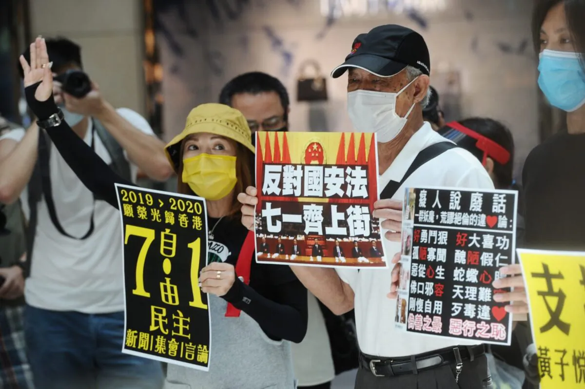 Protesters take part in a lunchtime protest in Central district, Hong Kong on June 30, 2020. They hold up signs calling on people to join a July 1 protest. (Song Bilung/The Epoch Times)