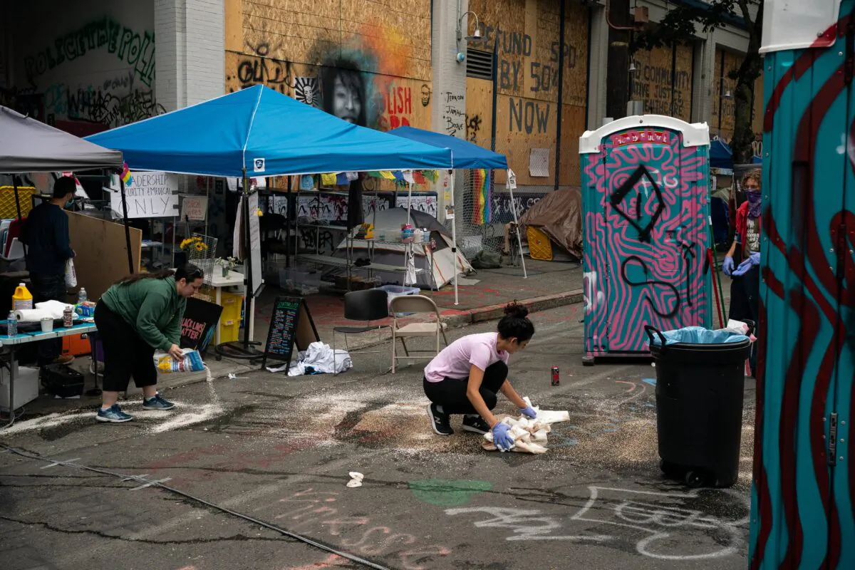 People clean the site of an early morning shooting that left one person dead and one in critical condition in the area known as the Capitol Hill Organized Protest (CHOP) in Seattle, Wash., on June 29, 2020. (David Ryder/Getty Images)