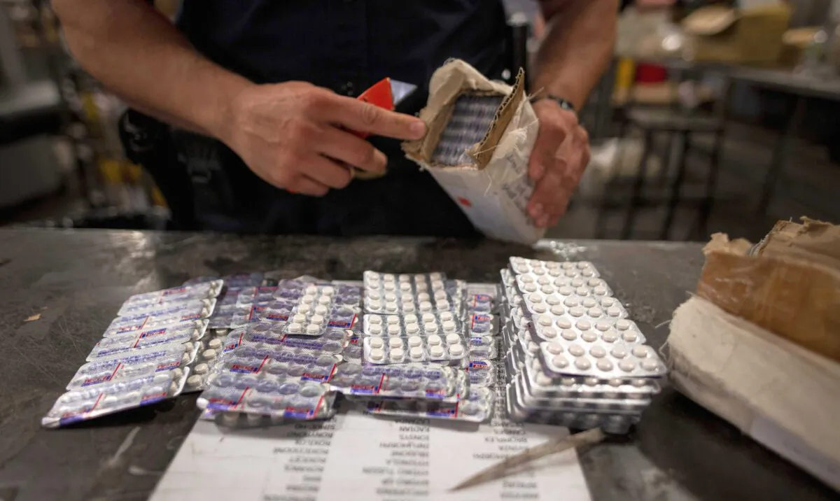 An officer from the U.S. Customs and Border Protection, Trade and Cargo Division finds Oxycodon pills in a parcel at John F. Kennedy Airport's U.S. Postal Service facility in New York on June 24, 2019. (Johannes Eisele/AFP via Getty Images)