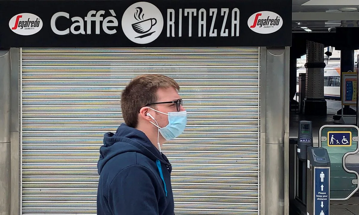 A pedestrian wearing a mask walks past a closed-down and shuttered Caffe Ritazza coffee and food outlet in a train station in London on July 1, 2020. (Daniel Leal-Olivas/AFP via Getty Images)