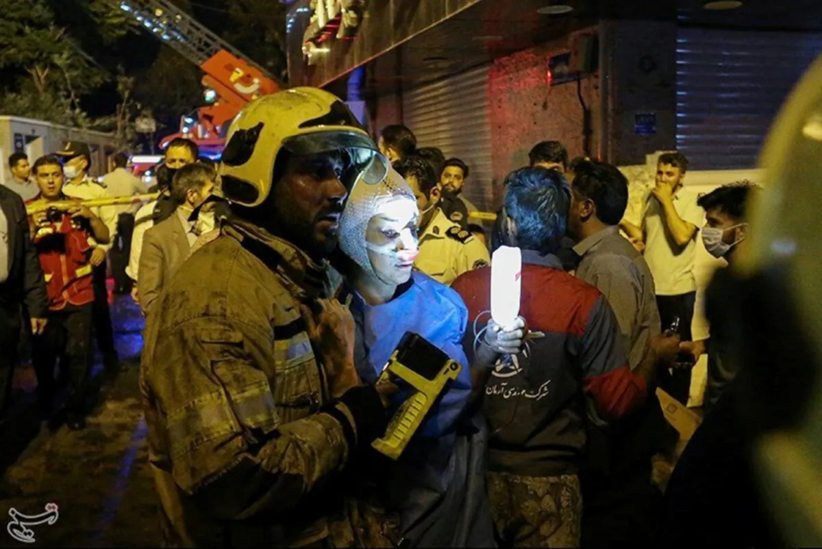 A firefighter helps an injured woman at the site of an explosion at a medical clinic in the north of the Iranian capital Tehran, Iran, on June 30, 2020. (Tasnim News Agency/Handout via Reuters)