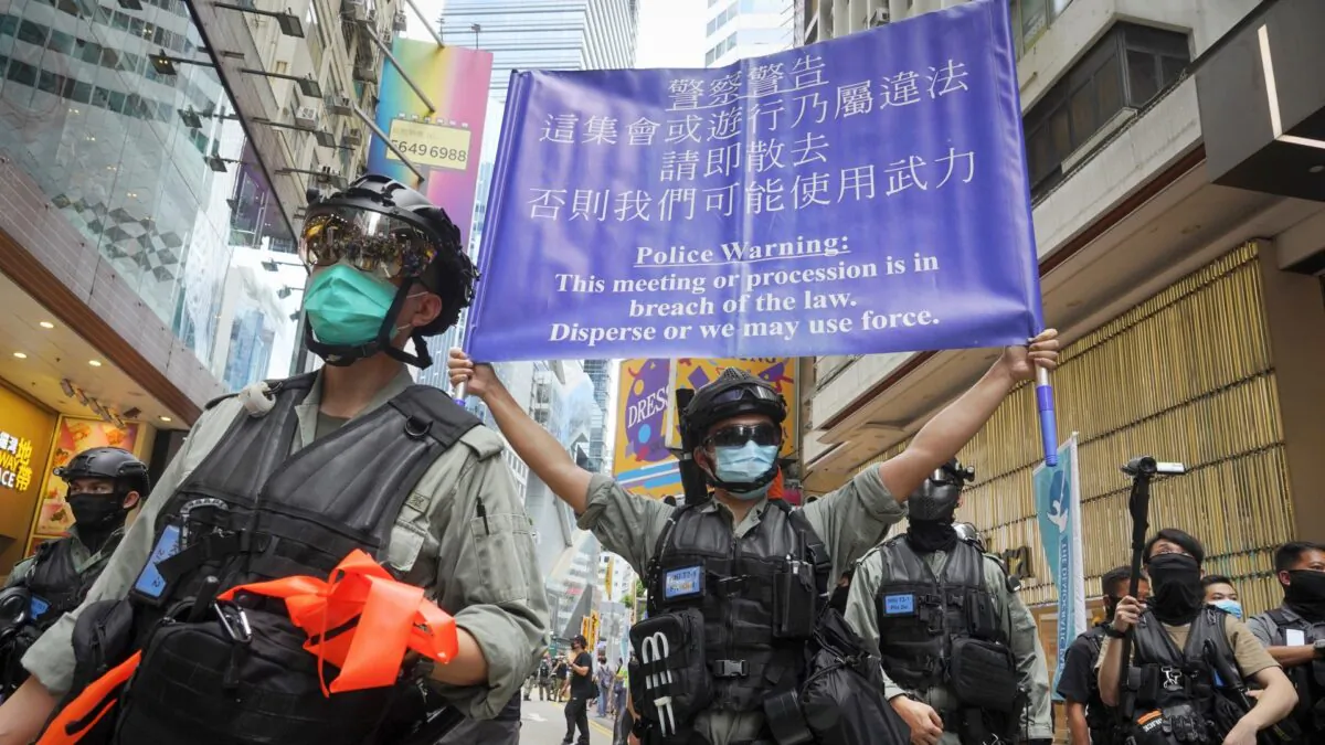 Police display a public announcement banner showing a warning to protesters in Causeway Bay before the annual handover march in Hong Kong on July 1, 2020. (Vincent Yu/AP)
