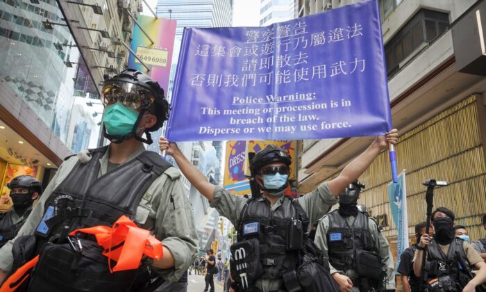 Police display a public announcement banner showing a warning to protesters in Causeway Bay before the annual handover march in Hong Kong on July 1, 2020. (Vincent Yu/AP)