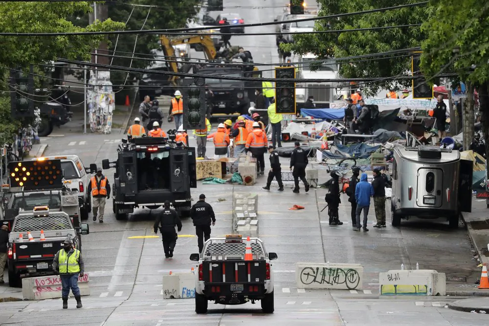 Police and city workers fill a street occupied hours earlier by an encampment of protesters in Seattle on July 1, 2020. (Elaine Thompson/AP)
