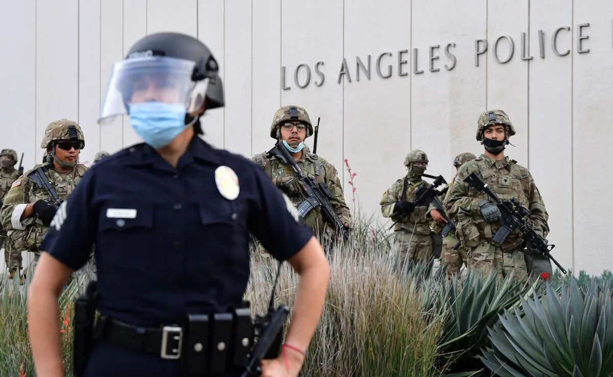 A police officer stands with armed members of the National Guard facing protesters in front of the Los Angeles Police Department in Los Angeles, California, on June 1, 2020. (Frederic J. Brown/AFP via Getty Images)