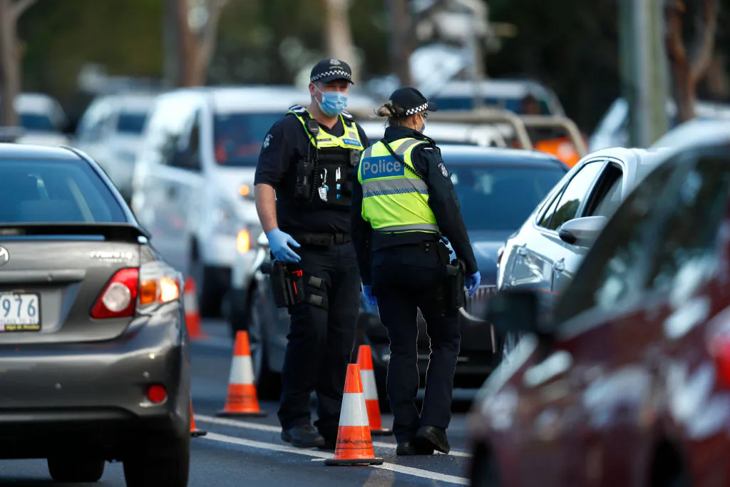 Police check the identification of members of the public at a pop up road block in Broadmeadows, Victoria to ensure they have legitimate reasons for leaving one of the 10 postcode hotspots on 2 July, 2020 in Melbourne, Australia. (Darrian Traynor/Getty Images)