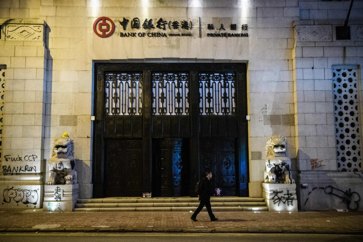 A man walks past graffiti left by protesters on the old Bank of China building following a pro-democracy rally from Victoria Park to Chater Road in Hong Kong on Dec. 8, 2019. (Anthony Wallace/AFP via Getty Images)