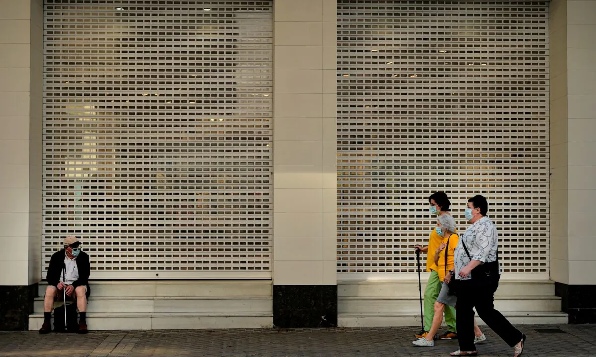 A group of women walk past beside a man seated while wearing face mask to prevent the coronavirus during the last day of the lockdown, in Pamplona, northern Spain, on June 20, 2020. (Alvaro BarrientosAP Photo)