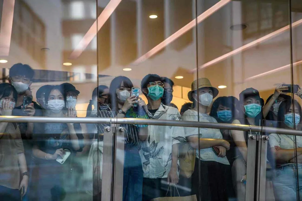 Bystanders watch protesters on a street below a shop during a rally against a new national security law in Hong Kong on July 1, 2020. (Anthony Wallace/AFP via Getty Images)
