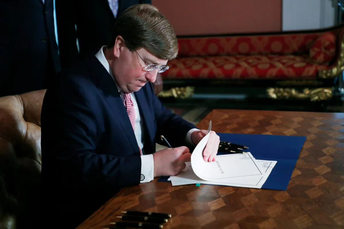Mississippi Gov. Tate Reeves signs the bill retiring the last state flag with the Confederate battle emblem during a ceremony at the Governor's Mansion in Jackson, Miss., on June 30, 2020. (Rogelio V. Solis/Pool/AFP via Getty Images)