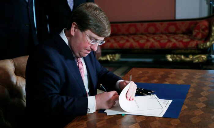 Mississippi Gov. Tate Reeves signs the bill retiring the last state flag with the Confederate battle emblem during a ceremony at the Governor's Mansion in Jackson, Miss., on June 30, 2020. (Rogelio V. Solis/Pool/AFP via Getty Images)