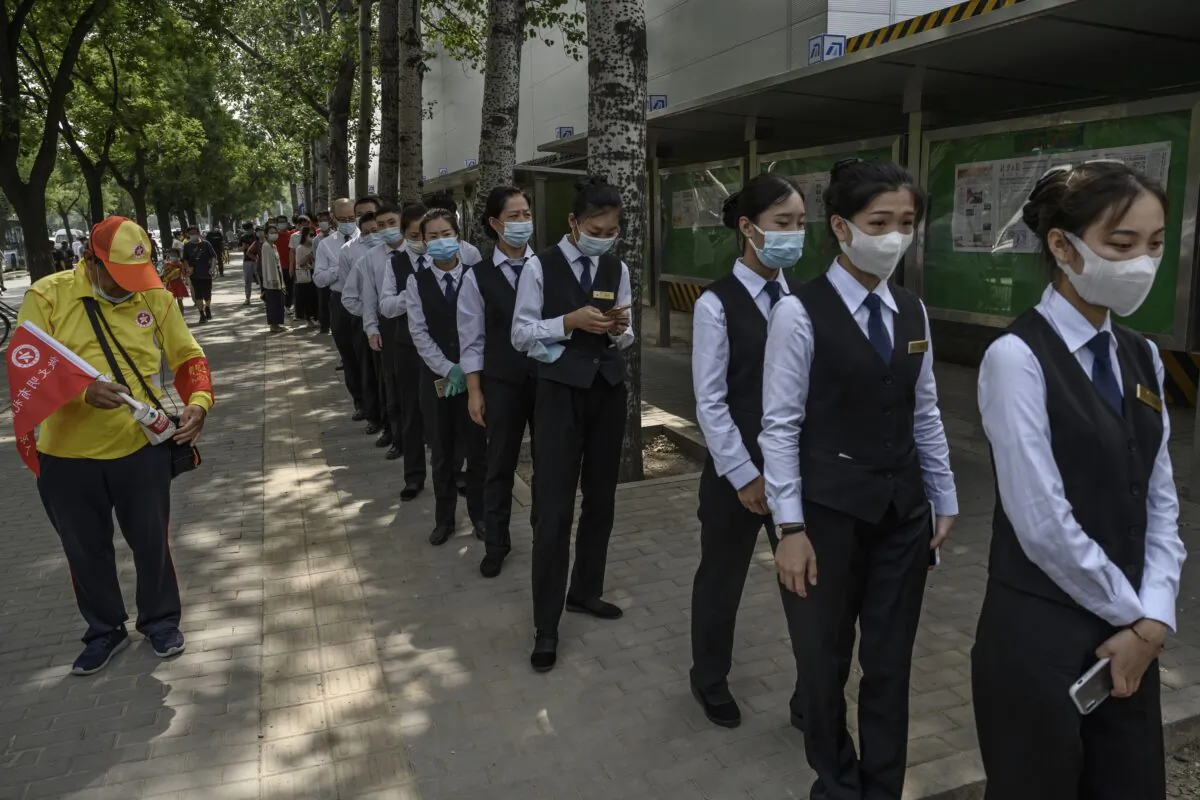 Chinese service industry workers wait in line for nucleic acid swab tests for COVID-19 at a testing site in Beijing on July 1, 2020. (Kevin Frayer/Getty Images)