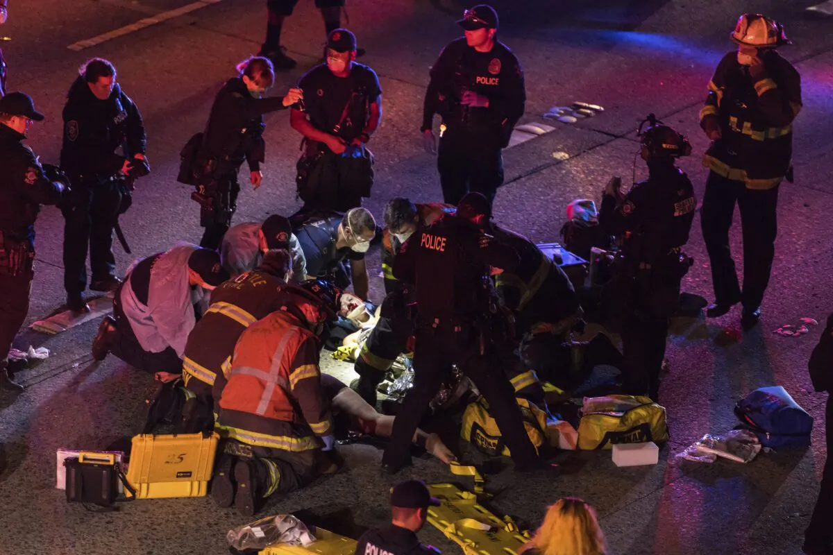 Emergency workers tend to an injured person on the ground after a driver struck two protesters on I-5 in Seattle, Wash., on July 4, 2020. (James Anderson via AP)