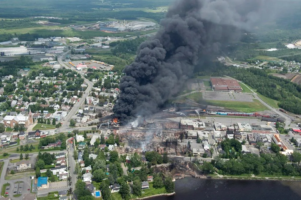 Smoke rises from railway cars that were carrying crude oil after derailing in downtown Lac-Mégantic, Que., on July 6, 2013. (Paul Chiasson/The Canadian Press)
