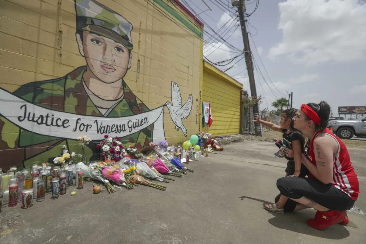 Dawn Gomez holds her 3-year-old granddaughter who waves at Vanessa Guillen's mural painted by Alejandro "Donkeeboy" Roman Jr. on the side of Taqueria Del Sol in Houston, Texas, on July 2, 2020. (Steve Gonzales/Houston Chronicle via AP)