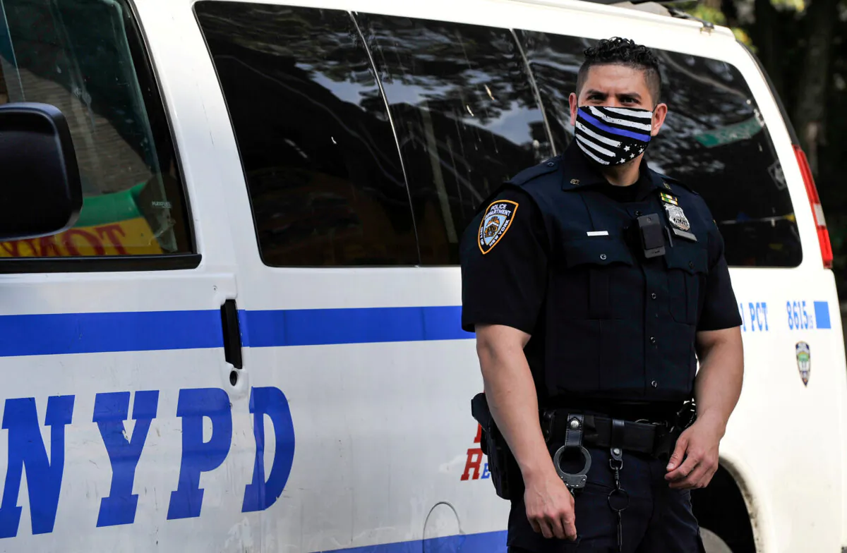A NYPD police offer wears a Blue Line mask indicating support for law enforcement at the scene of a shooting in Brooklyn, N.Y., on June 25, 2020. (Lloyd Mitchell/Reuters)