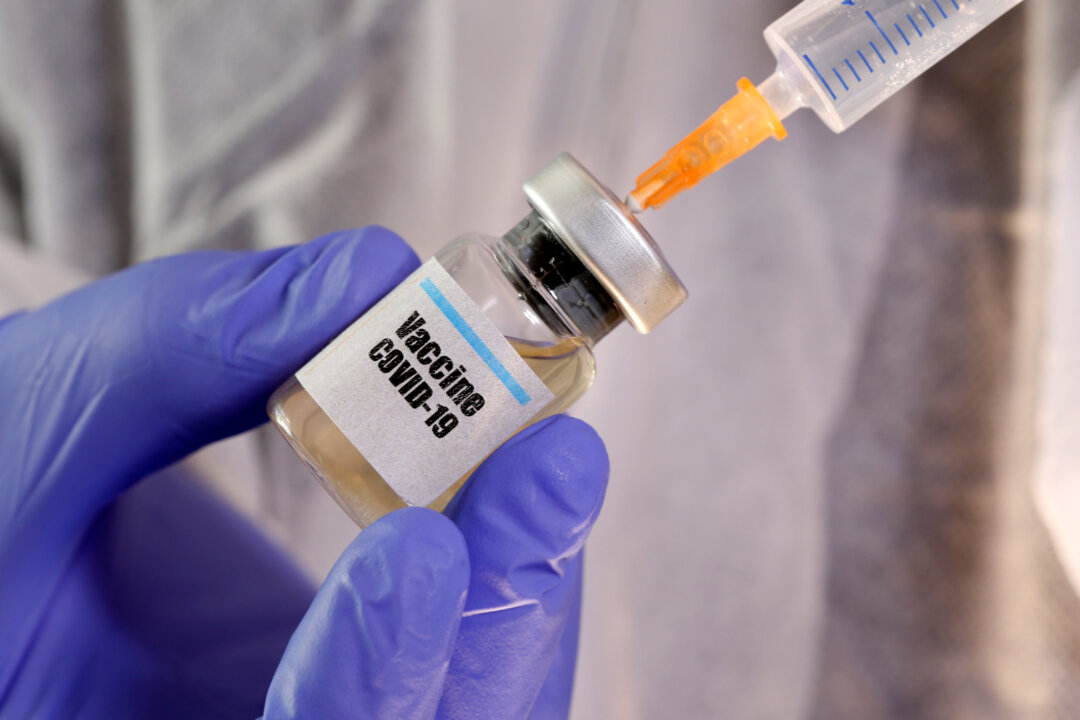 A woman holds a small bottle labeled with a "Vaccine COVID-19" sticker and a medical syringe in this illustration taken on April 10, 2020. (Dado Ruvic/Illustration/File Photo/Reuters)