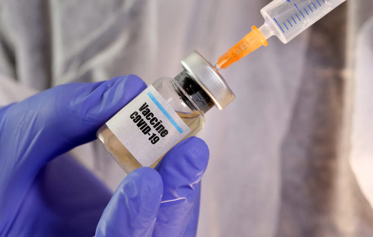 A woman holds a small bottle labeled with a "Vaccine COVID-19" sticker and a medical syringe in this illustration taken on April 10, 2020. (Dado Ruvic/Illustration/Reuters)