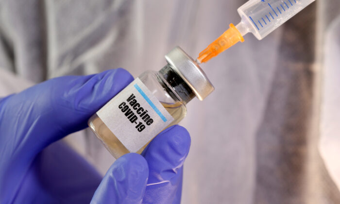 A woman holds a small bottle labeled with a "Vaccine COVID-19" sticker and a medical syringe in this illustration taken on April 10, 2020. (Dado Ruvic/Illustration/Reuters)
