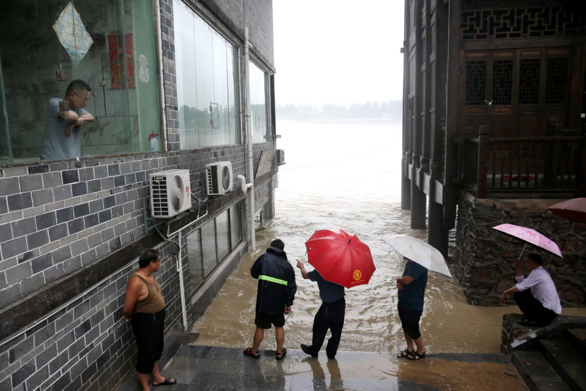People observe the rising water level of a river at the flood-hit Zhuoshui ancient town, following heavy rainfall in Chongqing's Qianjiang district, China, on June 28, 2020. (China Daily via Reuters)