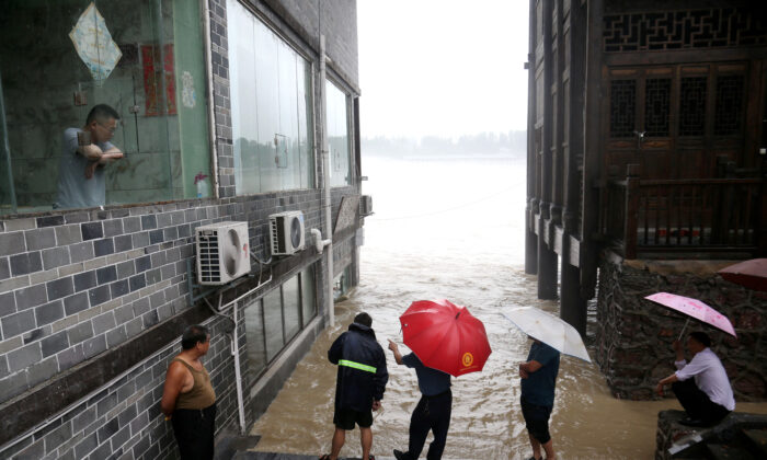 People observe the rising water level of a river at the flood-hit Zhuoshui ancient town, following heavy rainfall in Chongqing's Qianjiang district, China, on June 28, 2020. (China Daily via Reuters)