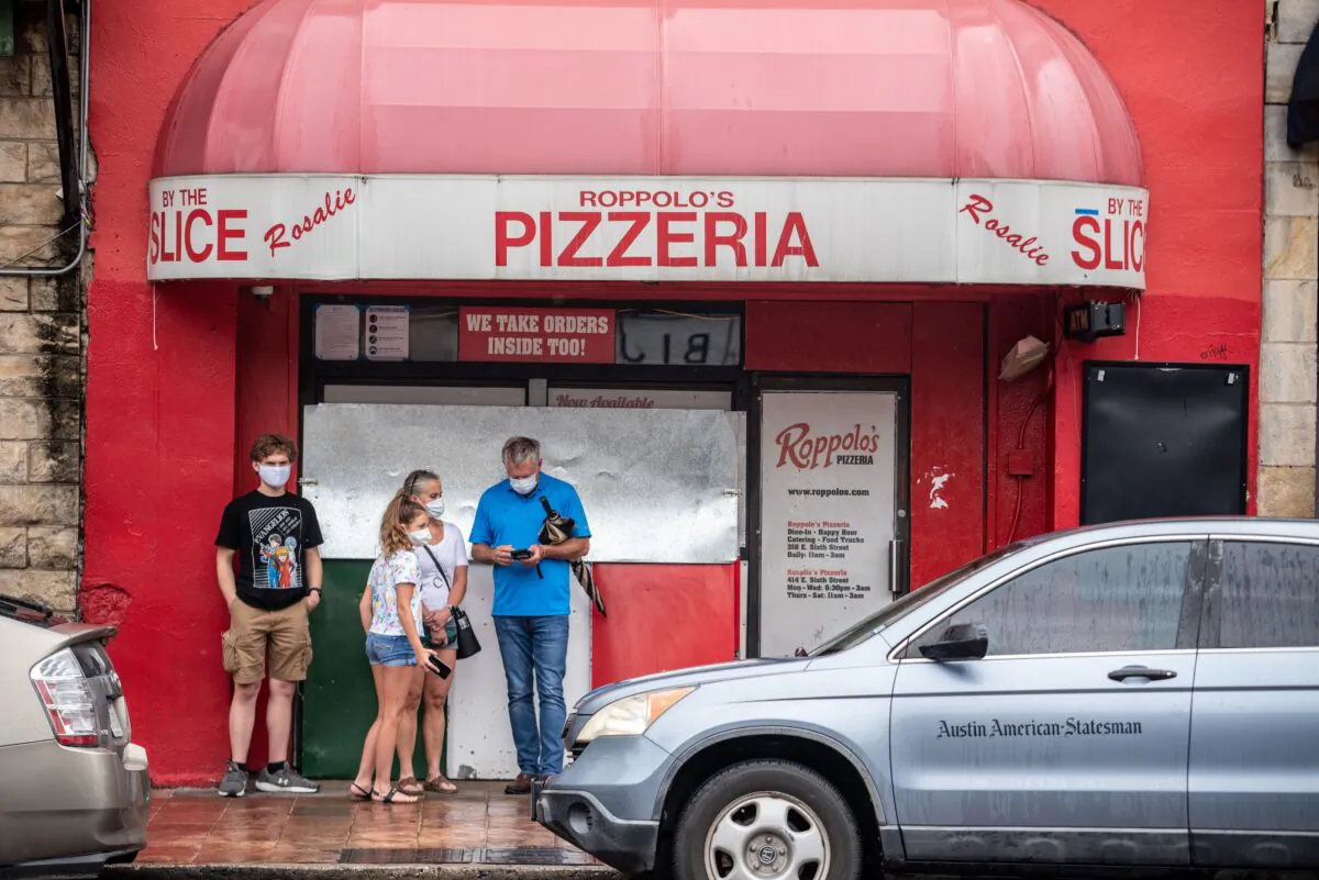 A family wearing facemasks stands in front of a pizzeria in Austin, Texas, on June 26, 2020. (Sergio Flores/AFP via Getty Images)