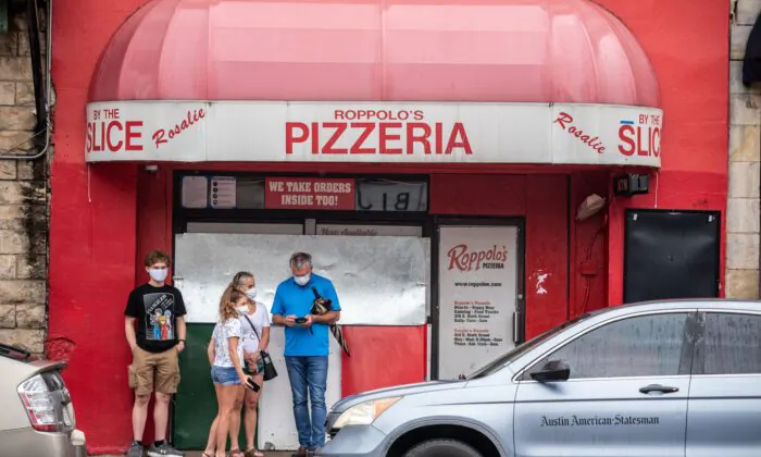 A family wearing facemasks stands in front of a pizzeria in Austin, Texas, on June 26, 2020. (Sergio Flores/AFP via Getty Images)