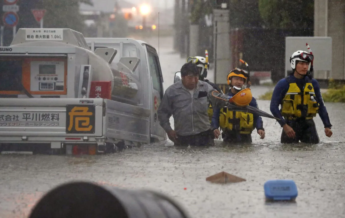 A man is rescued by police officers after his car became stuck on a flooded road caused by torrential rain in Omuta, Fukuoka prefecture, southern Japan, on July 7, 2020. (Kyodo/Reuters)