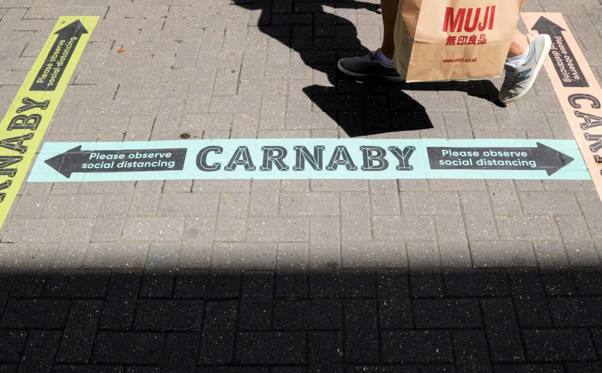 A shopper walks past social distancing signs in Carnaby Street, as the outbreak of the coronavirus disease (COVID-19) continues, in London, UK, on June 22, 2020. (Reuters/John Sibley)