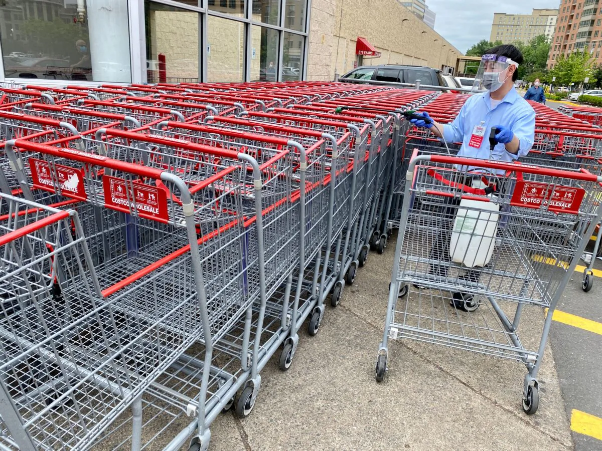 A Costco employee sprays disinfectant on shopping carts in Arlington, Va., on May 24, 2020. (Daniel Slim/AFP via Getty Images)