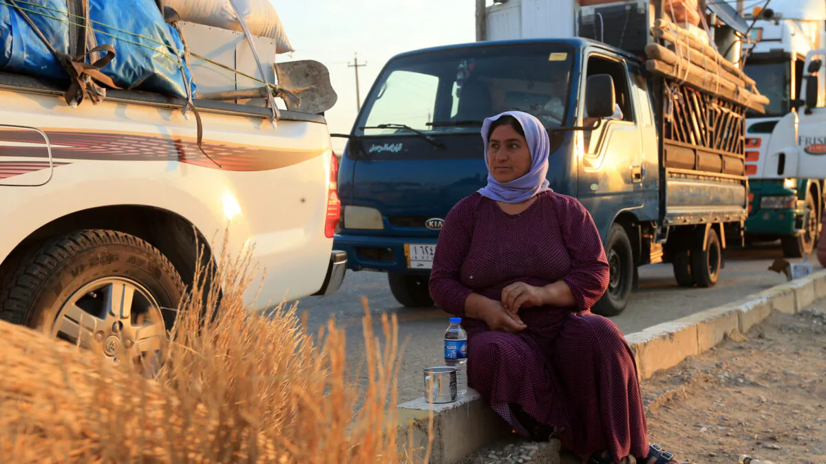 Wife of displaced Yazidi Nayef al-Hamo sits with her neighbours on the road as she heads back to Sinjar following the outbreak of the coronavirus disease (COVID-19) and economic crisis, near Dohuk, Iraq July 3, 2020. (Ari Jalal/Reuters)