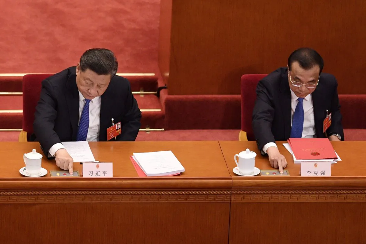 Chinese leader Xi Jinping (L) and premier Li Keqiang vote during the closing session of the regime’s rubber stamp legislature’s annual meeting in Beijing, China on May 28, 2020. (NICOLAS ASFOURI/AFP via Getty Images)