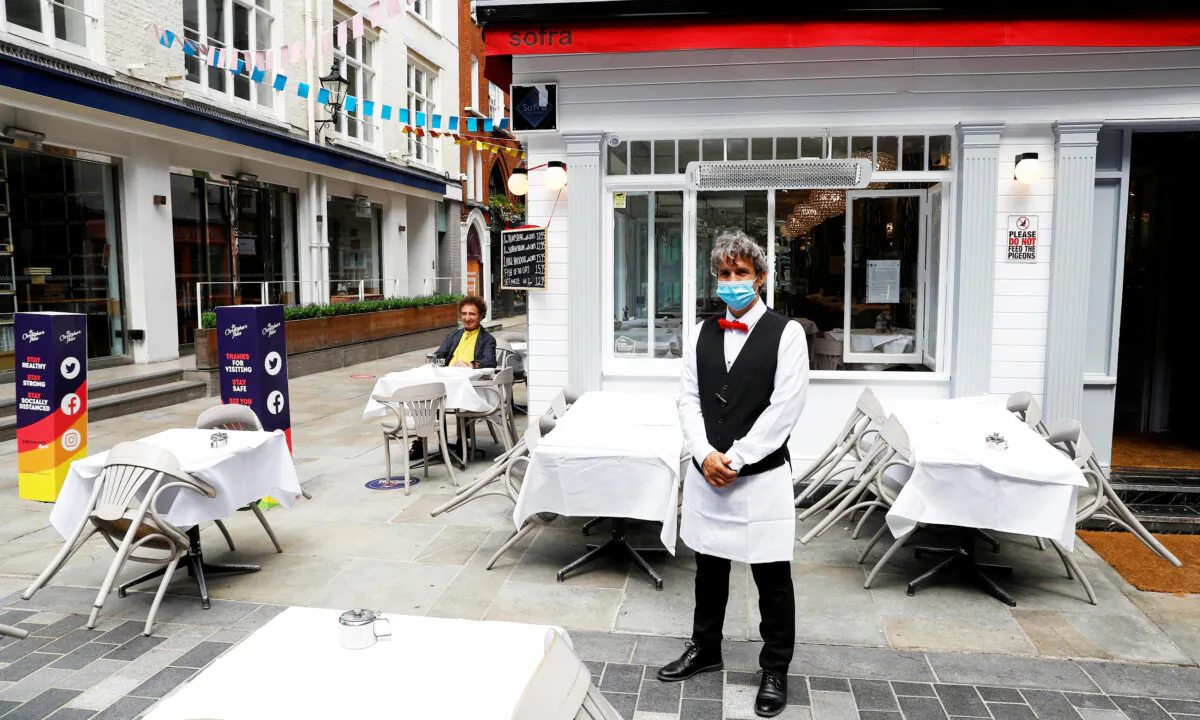 A waiter poses for photographs as he waits for customers outside a restaurant, after it reopened following the coronavirus disease (COVID-19) outbreak, in London, Britain, on July 5, 2020. (Peter Nicholls/Reuters)