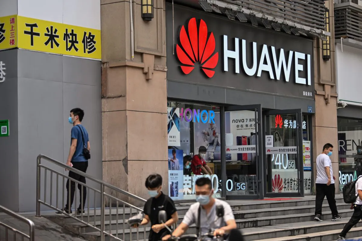 People wearing face masks walk past a Huawei store in Wuhan, in Chinas central Hubei Province on May 26, 2020. (HECTOR RETAMAL/AFP via Getty Images)