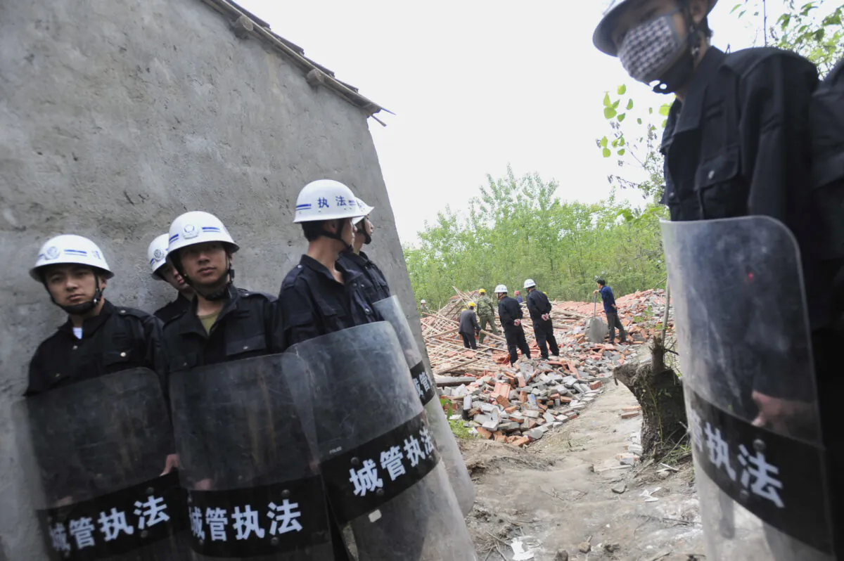 Chinese security agents carry sticks as they stand guard while workers demolish houses in Wuhan, central China's Hubei Province on May 7, 2010. (AFP/AFP via Getty Images)