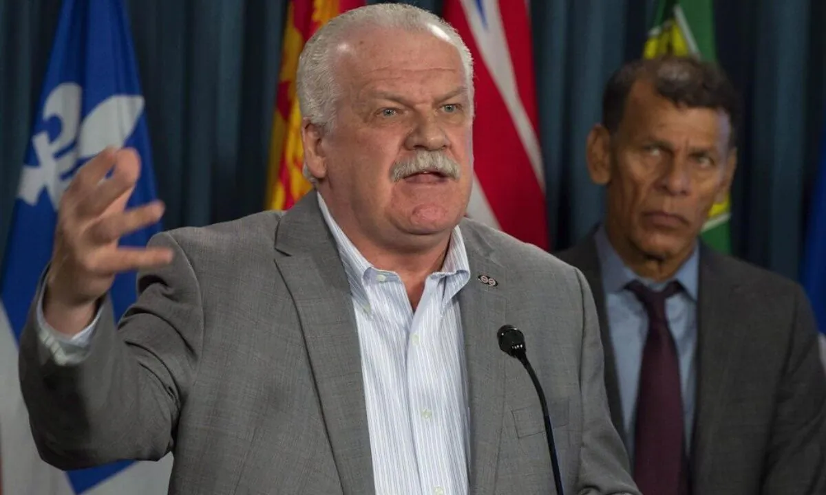 Canadian Labour Congress president Hassan Yussuff (R) looks on as Public Service Alliance of Canada president Chris Aylward speaks duding a news conference about pay equity in Ottawa, on October 31, 2018. (Adrian Wyld/The Canadian Press)