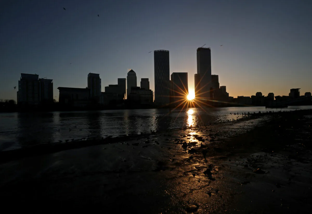 The sun rises behind the Canary Wharf financial district in London on Feb. 12, 2020. (Hannah McKay/Reuters)