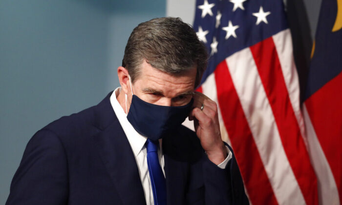 Gov. Roy Cooper prepares to take off his mask before speaking during a briefing at the Emergency Operations Center in Raleigh, N.C., on July 9, 2020. (Ethan Hyman/The News & Observer via AP) 