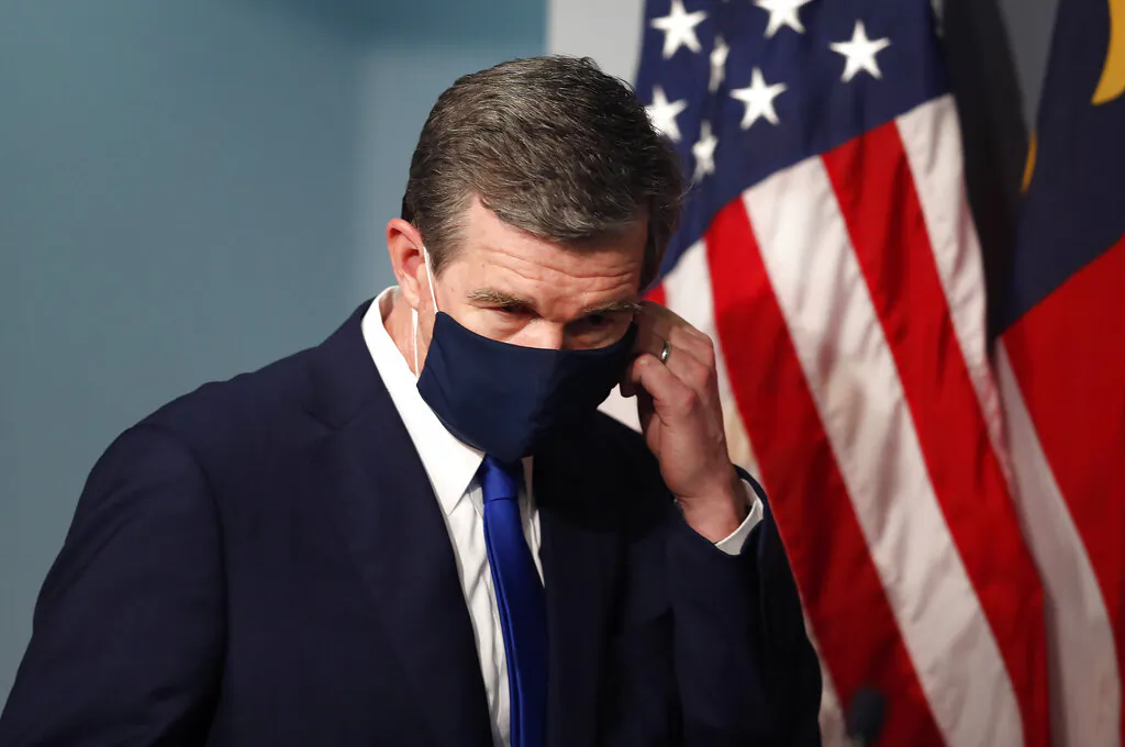 Gov. Roy Cooper prepares to take off his mask before speaking during a briefing at the Emergency Operations Center in Raleigh, N.C., on July 9, 2020. (Ethan Hyman/The News & Observer via AP) 