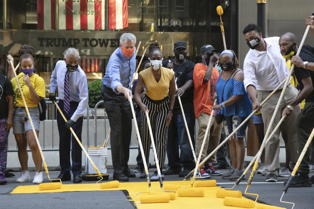 Mayor Bill de Blasio, third from left, participates in painting Black Lives Matter on Fifth Avenue in front of Trump Tower, in New York on July 9, 2020,. The mayor's wife, Chirlane McCray, is fourth from left and Rev. Al Sharpton is second from left. (AP Photo/Mark Lennihan)