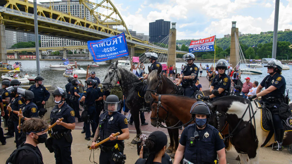 Pittsburgh Police in riot gear intervene between a group of Black Lives Matter protestors confronting a group of Trump supporters while they wait along the Allegheny River North Shore for a flotilla of boats taking part in a boat parade for the re-election of President Donald Trump to pass by on July 4, 2020 in Pittsburgh, Penn. (Jeff Swensen/Getty Images)