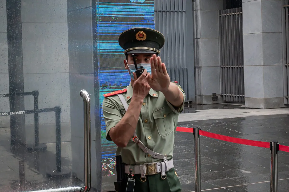 A Chinese paramilitary police officer gestures and speaks over his two-way radio whlie standing at the entrance gate of the Australian embassy in Beijing on July 9, 2020. (Nicolas Asfouri/AFP via Getty Images)